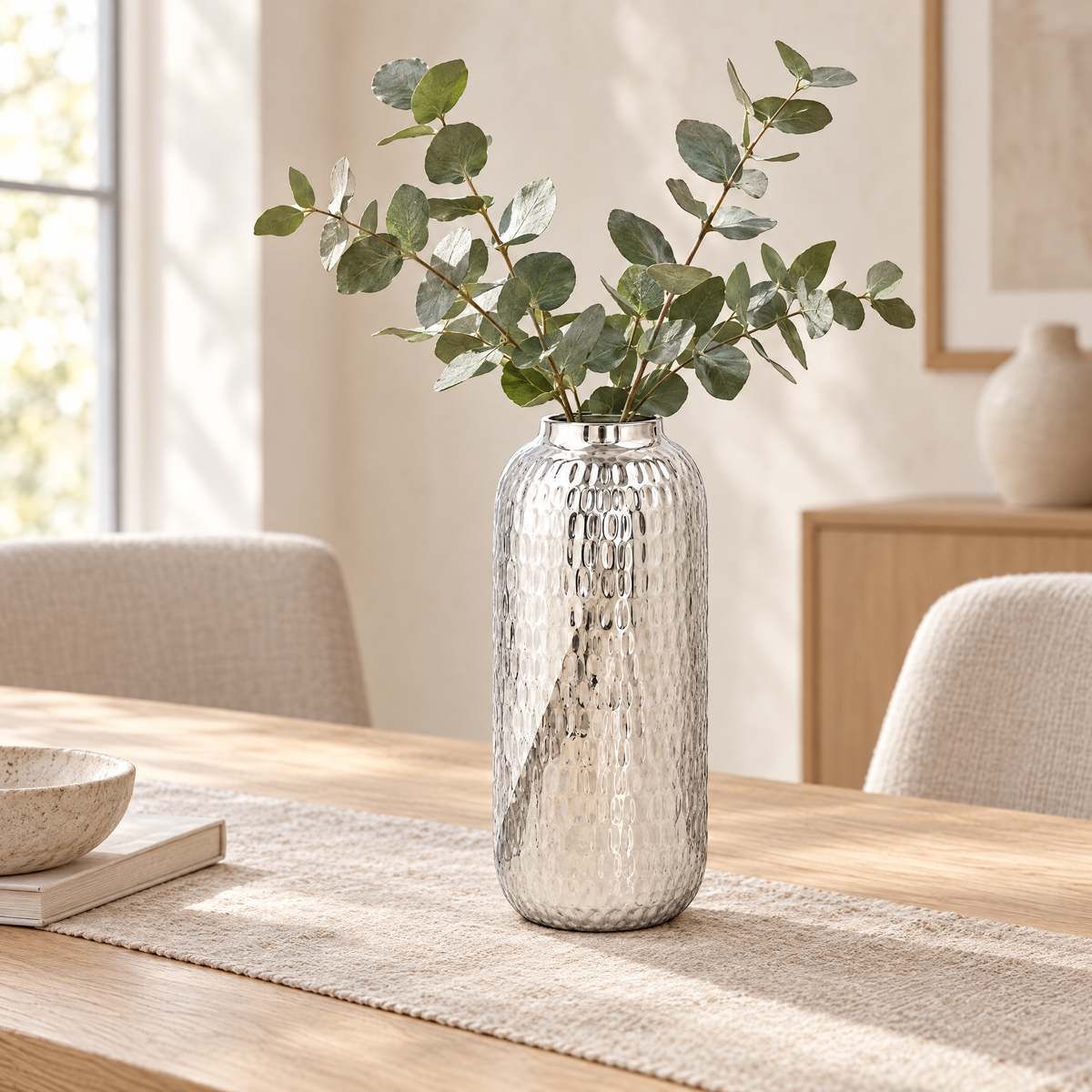 Silver hammered barrel vase with eucalyptus on a dining table