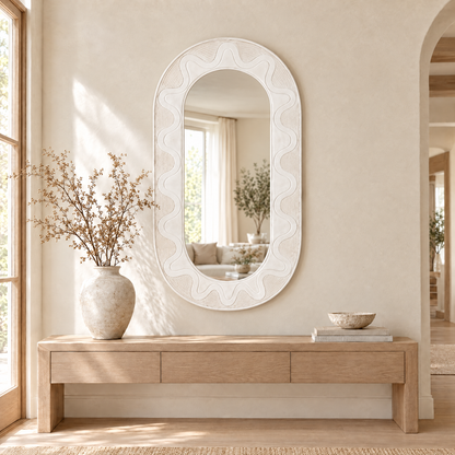 Large white carved capsule mirror above an oak console in an entrance hall